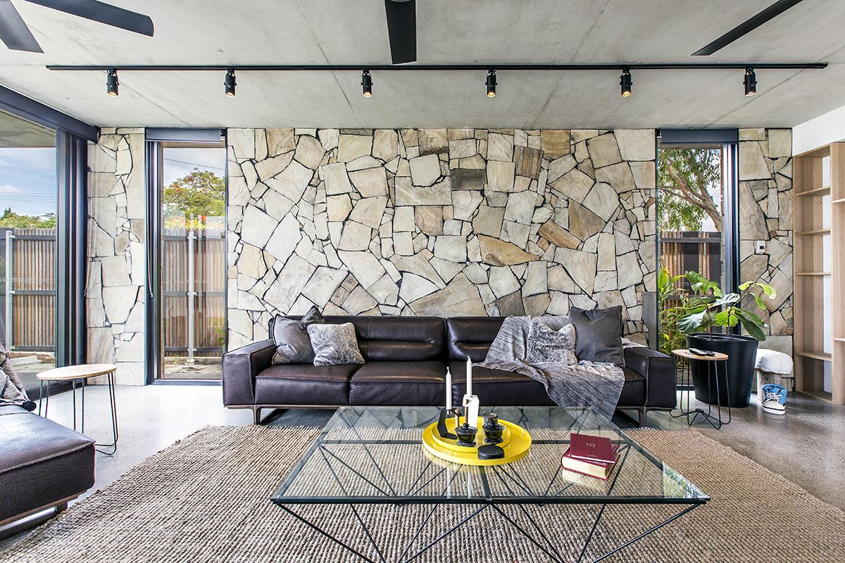 Open-plan living space with a stone feature wall, photographed for a design project
